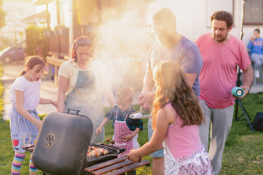 Picture of big happy family making barbeque in their backyard. Family time on sunny summer day.Family goals.