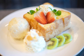 Honey Toast served with vanilla ice cream, whipped cream, strawberry and giwi 