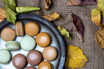 top view - rustic plate of macaroons on woven natural material, surrounded by autumn leaves