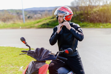 Young handsome man sitting on his bike with helmet in his hands.