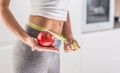 Woman holding red apple and measure tape.