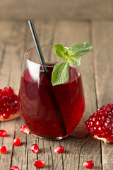 A glass of pomegranate juice with fresh pomegranate fruits on wooden table. Vitamins and minerals. Healthy drink concept.