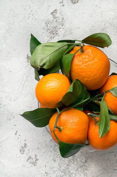 Fresh mandarins with leaves on a concrete table. Top view. Vertical photo. 