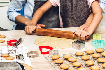 Mother and daugthter having fun cooking togather and learning to make a cake while baking in kitchen at home