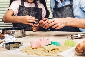 Mother and daugthter having fun cooking togather and learning to make a cake while baking in kitchen at home