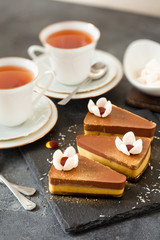 Cup of tea with portion mousse cake over dark background