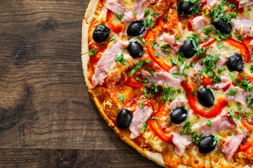 Pizza with Mozzarella cheese, ham, pepper, meat, Tomatoes, olives, Spices and Fresh Basil. Italian pizza on wooden background