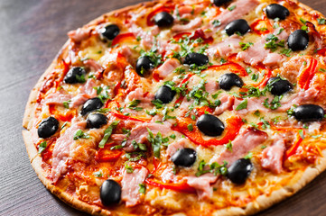Pizza with Mozzarella cheese, ham, pepper, meat, Tomatoes, olives, Spices and Fresh Basil. Italian pizza on wooden background