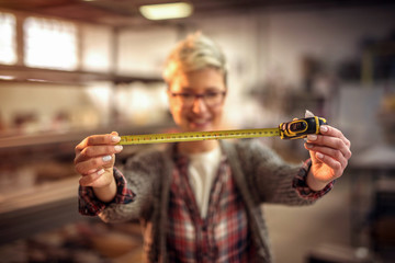 Young female designer in her workshop shoving measuring instrument in front of the camera.