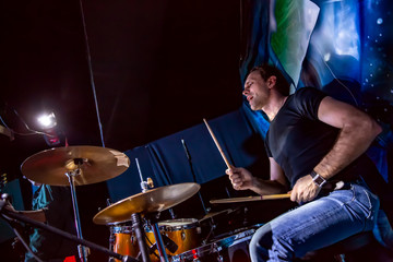 Drummer playing on drum set on stage.