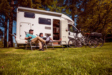 Woman with a man resting near motorhomes in nature. Family vacation travel, holiday trip in motorhome RV, Caravan car Vacation.