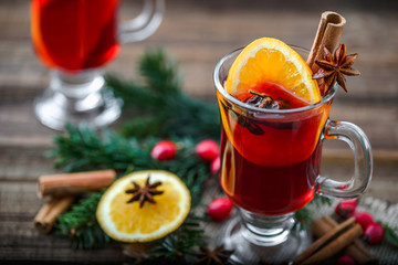 Mulled wine with orange slice and spices or tea glass, hot drink on christmas table
