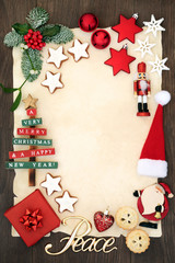 Christmas party invitation or blank letter to santa claus concept with peace sign, decorations, mince pie, gingerbread biscuits and winter flora on parchment on rustic oak background.