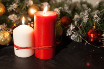 Christmas candles on the background of branches of a Christmas tree and glowing garlands