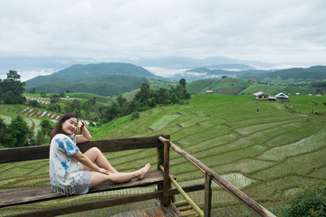 Fototapeta na wymiar The pretty woman relaxing in holiday at rice terrace, Rice planting season in Chiang Mai, Tourism concept