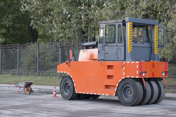 Heavy machinery against hand tools. Road construction working. Roller compactor machine for pressing new asphalt. Road renewal process.
