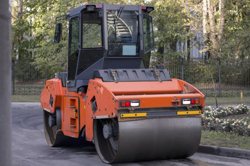 Road construction working. Heavy Vibration roller compactor flatten out new asphalt. Road renewal process.