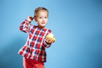 Fototapeta na wymiar Portrait of cute little girl with toy on blue background.