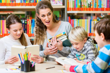 Teacher with her class visiting the library reading books for education