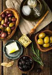 Assorted of marinated olives with cheese and rosemary on a dark background