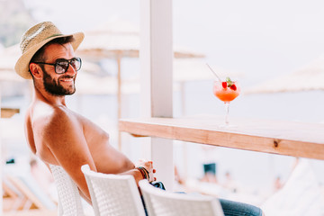 Young man enjoying cocktail in a beach bar