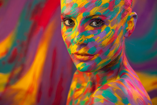 Portrait of the bright beautiful girl with brush, art colorful make-up face art and bodyart