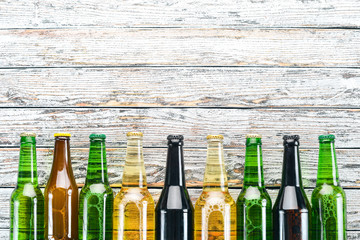 A large selection of beer bottles. On a white wooden table. Free space for text. Top view.