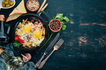 Traditional Israeli Cuisine dishes Shakshuka. Eggs with bacon and mushrooms. On a wooden background. Free space for text. Top view.