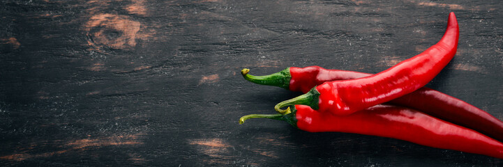 Chili red pepper. On a black wooden background. Free space for text. Top view. - obrazy, fototapety, plakaty