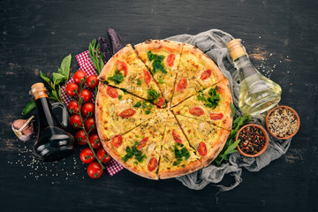 Pizza with cherry tomatoes, suluguni cheese and basil. Italian cuisine. On a wooden background. Free space for text. Top view.