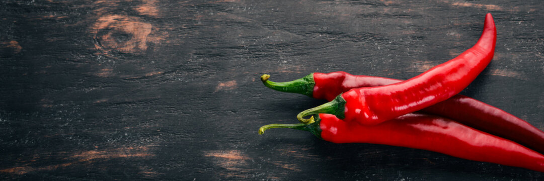 Chili red pepper. On a black wooden background. Free space for text. Top view.