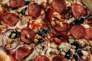 Pizza with sausage mushrooms cheese onion chicken close up.