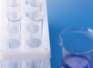 Test-tubes and flask with blue liquid on blue background