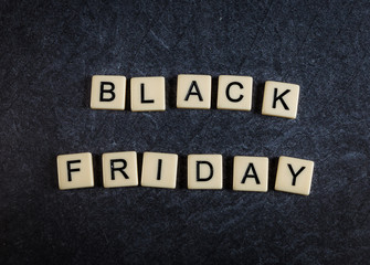 Scrabble letter tiles on black slate background spelling Black Friday