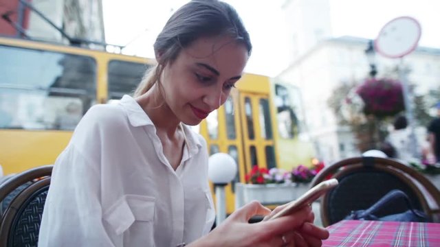 Smartphone girl using app on phone drinking coffee smiling in cafe. Beautiful young casual female professional on mobile phone.