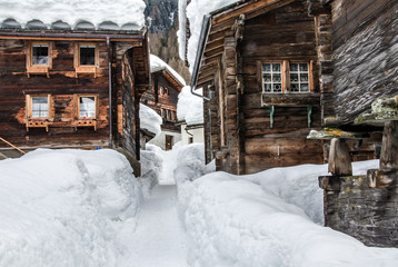 Snow covered old houses made of wood in alpine valley in Switzerland, Europe