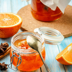 Close up of homemade orange jam in glass jar on blue background