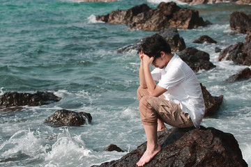 Stressed depressed Asian man covering face with hands and bend down head