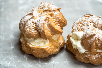 sweet, sprinkled with powdered sugar cream puffs on a light, stony background