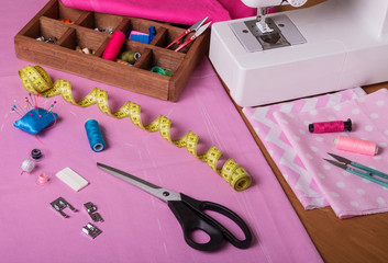 The workplace of seamstress. Cut-outs of colorful fabrics, accessories for sewing, sewing machine