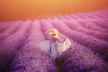 Woman in lavender flowers field at sunset in purple dress. France, Provence. Concept travel.