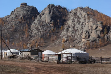 Mountain range and rock formation with gers, yurts and a barn in autumn fall at Terelji National Park, Mongolia