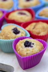 Banana muffins with chocolate, blackberries, strawberries, nuts and raisins in silicone molds on wooden mat, colorful hearts