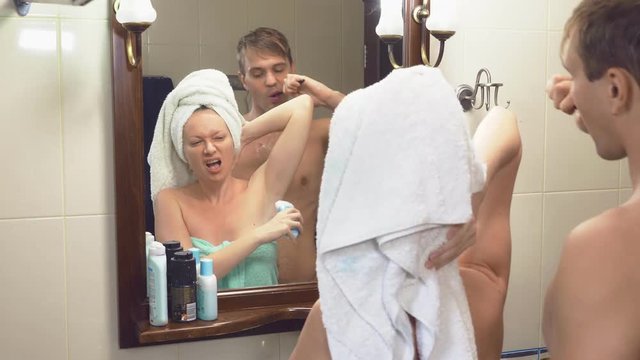 beautiful couple, man and woman, wash together in the bathroom in front of the mirror. 4k, slow motion, they interfere with each other standing in front of the mirror