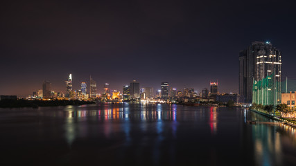 Fototapeta premium Miejski panoramę nocną panoramę miasta Ho Chi Minh. Widok z przodu na kolorowe drapacze chmur w centrum miasta od rzeki