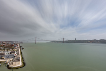 Wide top view 25 de Abril Bridge in Lisbon over Tagus river, ultra long exposure