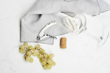 grapes, corkscrew, wine stopper and glass with white wine