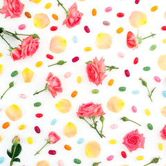 Fototapeta na wymiar Pattern made of roses flowers and petals with bright sugar candy on white background. Flat lay, top view.