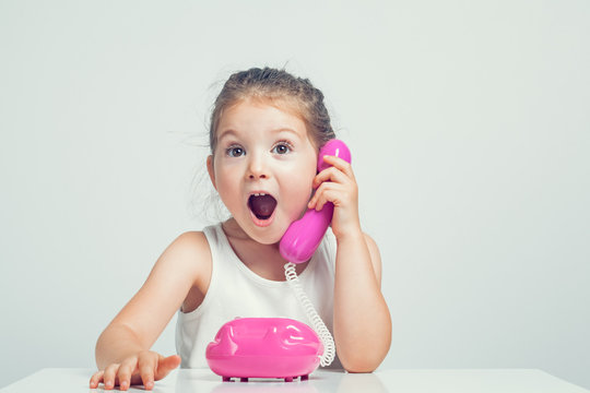 beautiful cute little girl talking on toy telephone with very excited expression