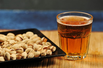 pistachios in a plate and a glass of beer